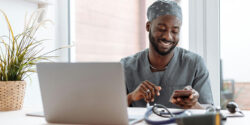 Physician wearing scrubs sitting at his laptop taking a medical survey for money.
