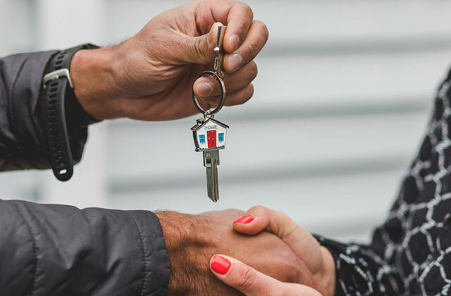 Real estate agent passing a house key to a client.