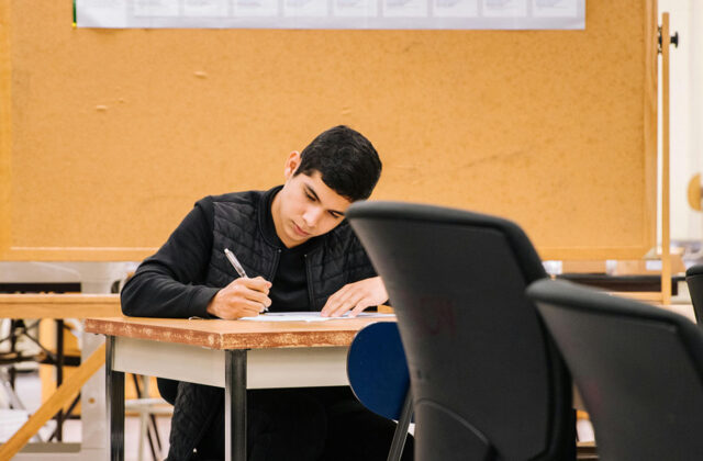 Grad student sitting at a desk working on a project for his side hustle.