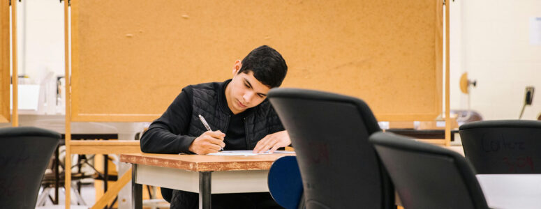 Grad student sitting at a desk working on a project for his side hustle.
