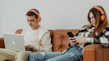two teenagers using job apps on a phone and laptop