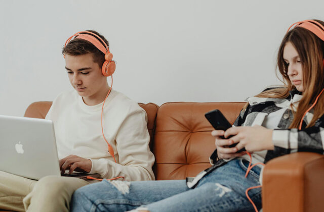 two teenagers using job apps on a phone and laptop