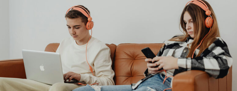 two teenagers using job apps on a phone and laptop