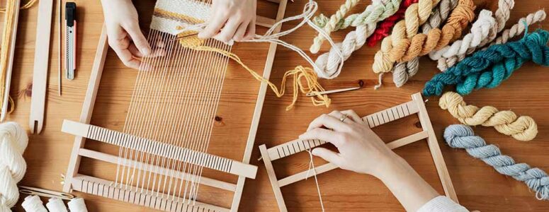 Hands of two professional crafters weaving a rug to sell for profit