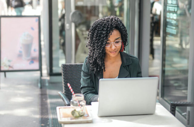 Freelancer sitting at her laptop searching for work on freelance writing websites.