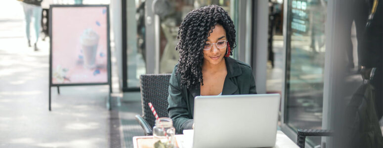 Freelancer sitting at her laptop searching for work on freelance writing websites.