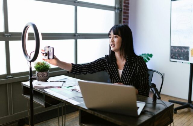 A young influencer setting up her camera so she can film herself in the office.
