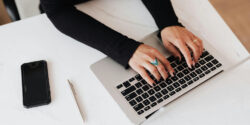 Close view of someone's hands on their keyboard as they work on a home-based typing side hustle.