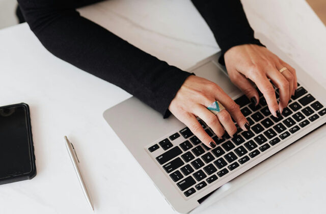 Close view of someone's hands on their keyboard as they work on a home-based typing side hustle.