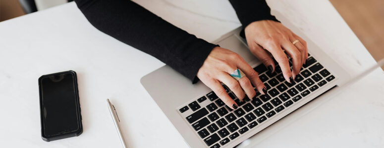 Close view of someone's hands on their keyboard as they work on a home-based typing side hustle.