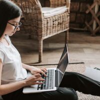 Freelance writer sitting on the floor working on a project on her laptop.