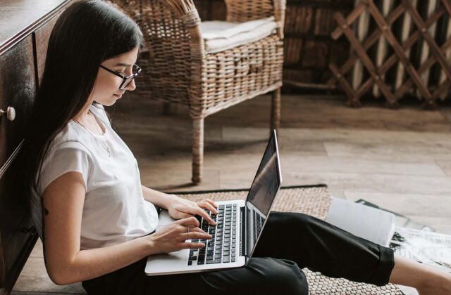 Freelance writer sitting on the floor working on a project on her laptop.