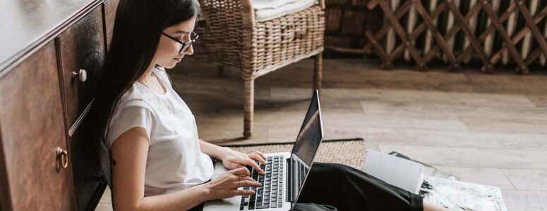 Freelance writer sitting on the floor working on a project on her laptop.