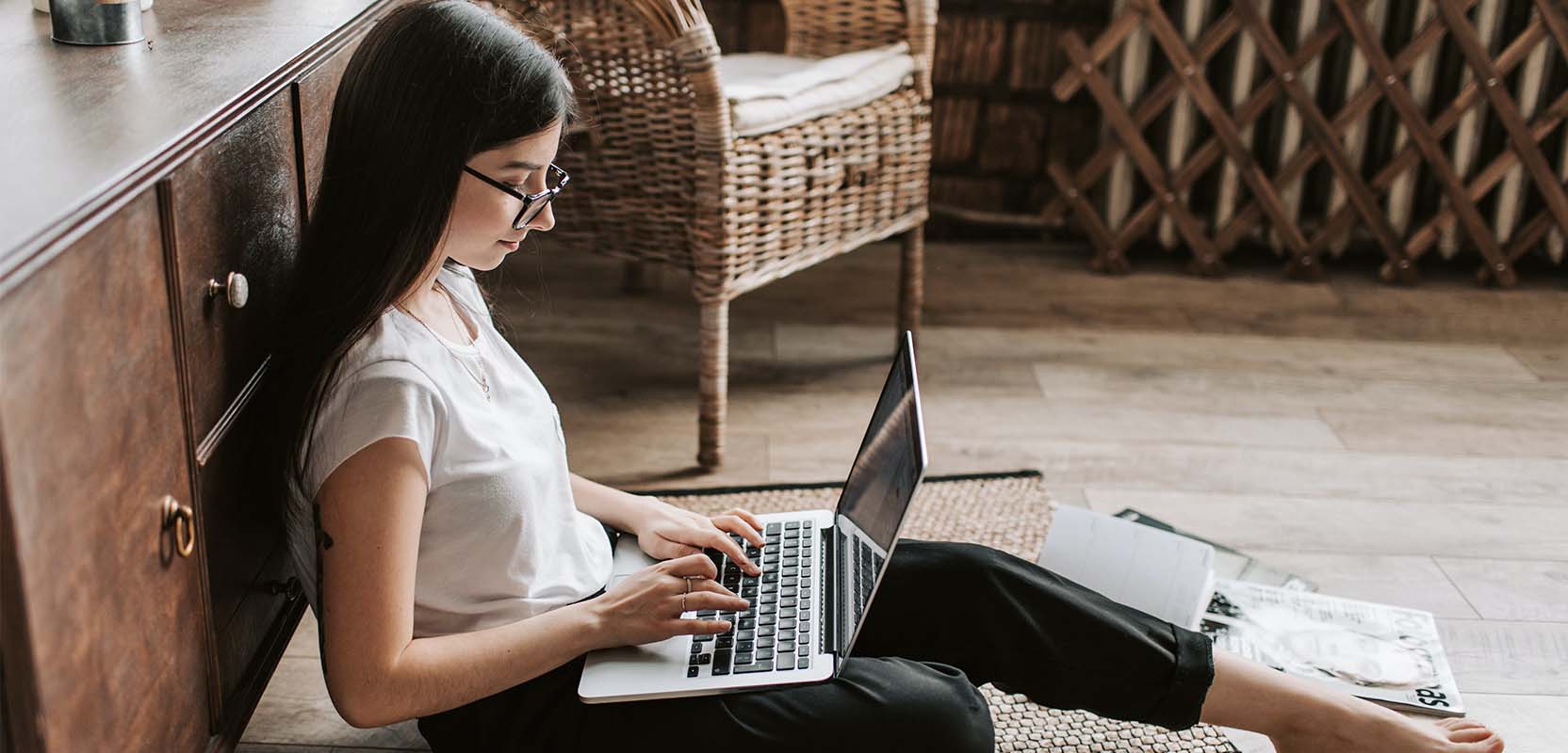 Freelance writer sitting on the floor working on a project on her laptop.