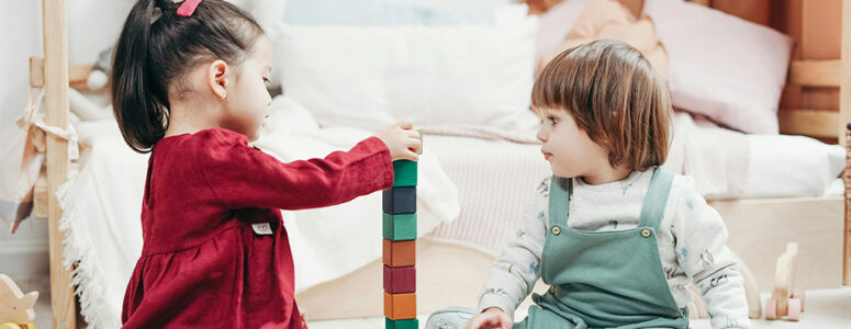Two preschool-aged toddlers playing with colored blocks at a home daycare