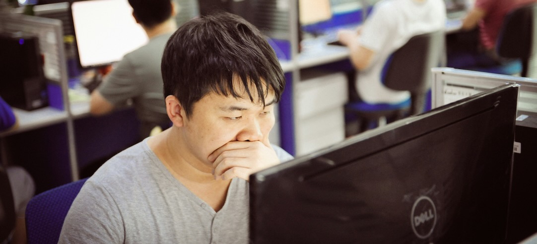An Asian worker staring hard at his computer.