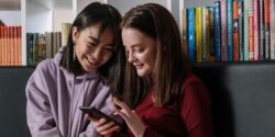 Two teenage girls taking a paid survey on a smartphone.
