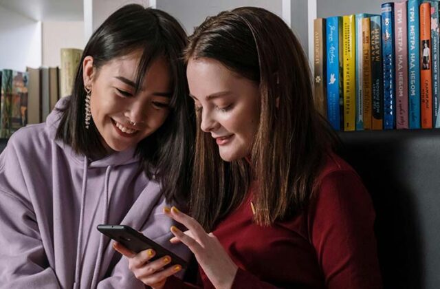 Two teenage girls taking a paid survey on a smartphone.