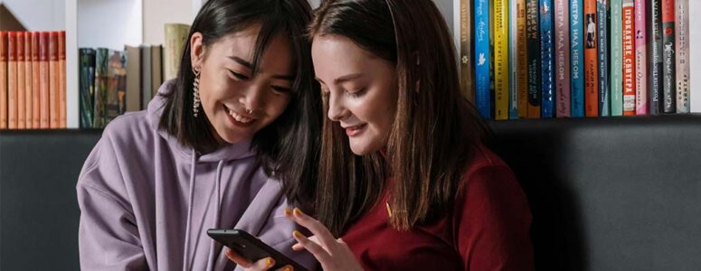 Two teenage girls taking a paid survey on a smartphone.