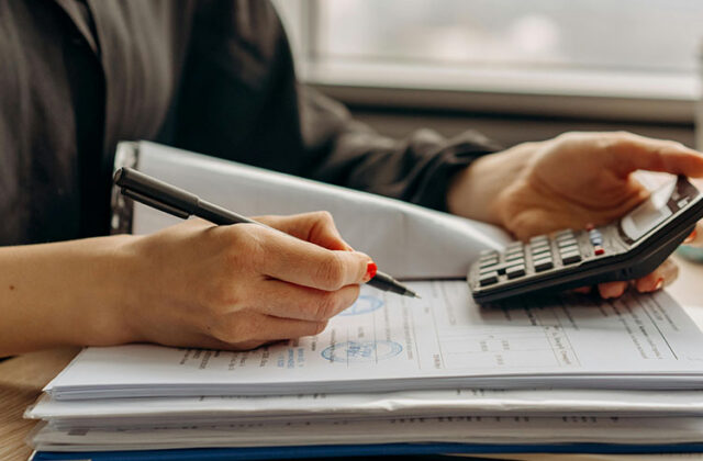 Accountant working on a calculator and taking notes for their side hustle.
