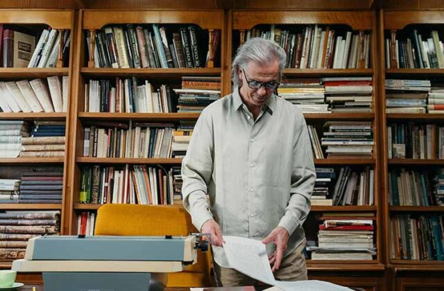 Older librarian handling a book for his side hustle as a book flipper.