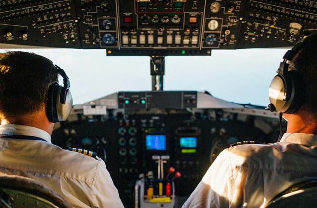 Pilot sitting in a cockpit chatting about side hustles with his copilot.