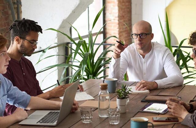 Project manager sitting at his laptop consulting with a client for his side hustle.