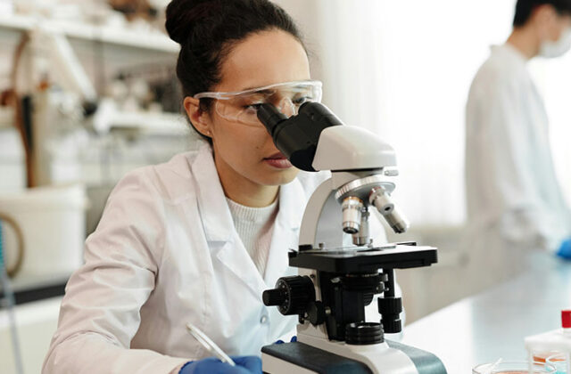 Scientist looking into a microscope in a lab.