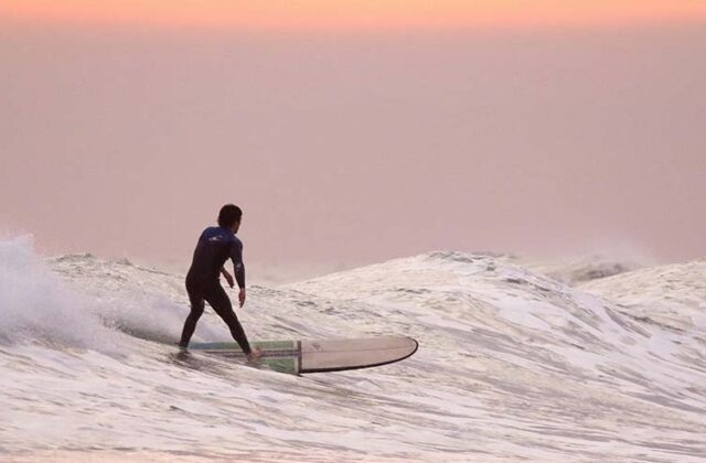 Man surfing on a break from his summer side hustle as a lifeguard.