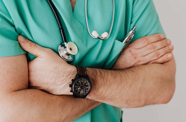 Close view of a physician dressed in blue scrubs.