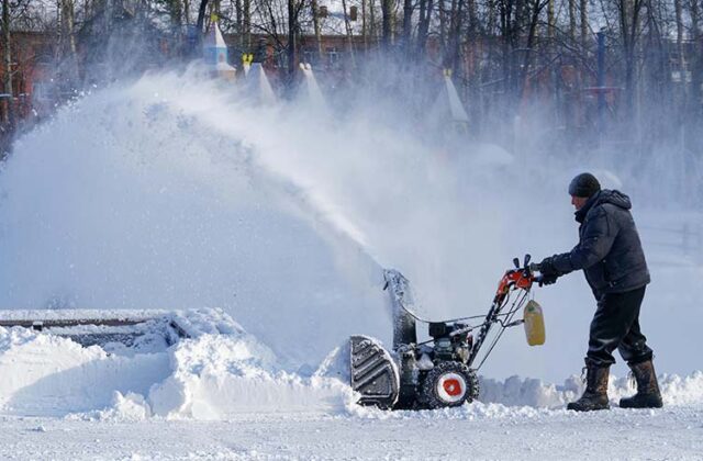 Man pushing a snowblower for his snow removal side hustle.