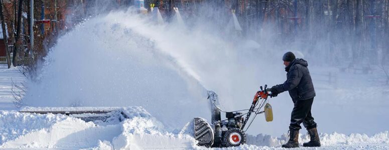 Man pushing a snowblower for his snow removal side hustle.