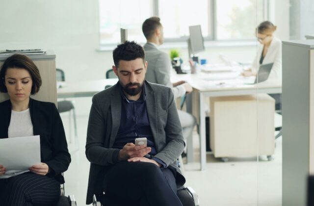 A man sitting in an office waiting to be called for a job interview.