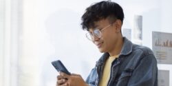 A man smiling and using his phone.