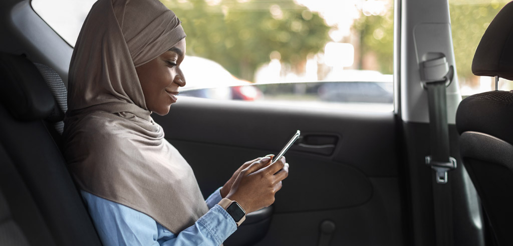 Female Uber passenger sitting in a car and holding her smartphone to leave a rating for the ride she just completed