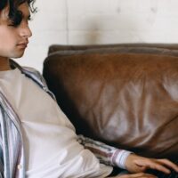 Transcriber on his couch completing a Babbletype assignment on his laptop.