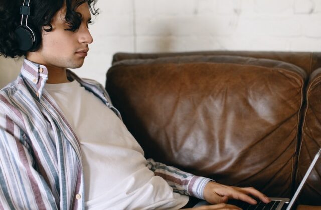 Transcriber on his couch completing a Babbletype assignment on his laptop.