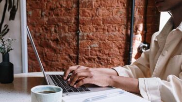 Blogger at a desk with coffee, typing up a blog post with one of the top blogging platforms