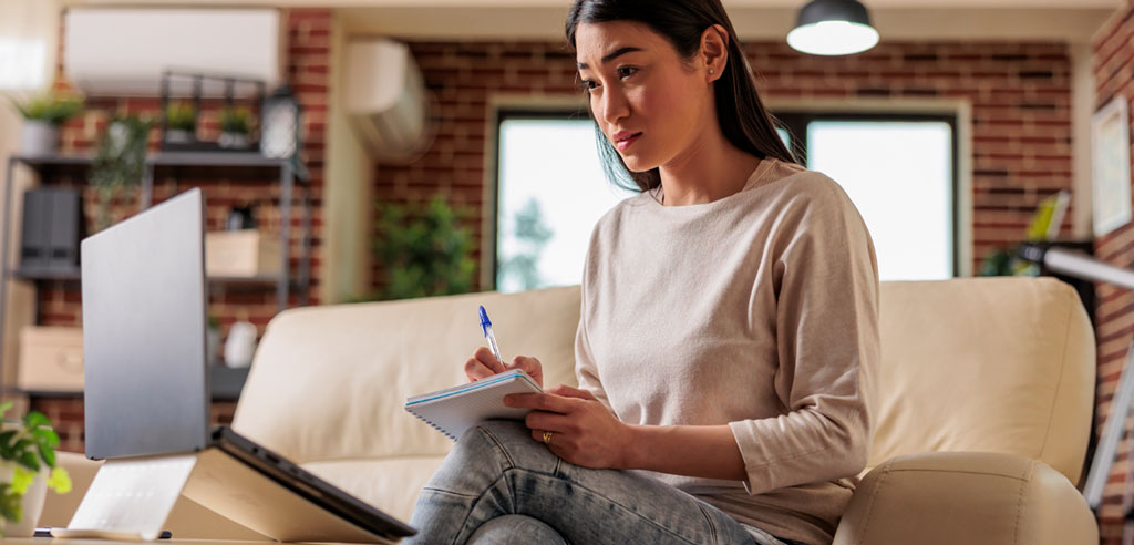 Female tutor taking note from a laptop while brushing up on her knowledge for her tutoring side hustle
