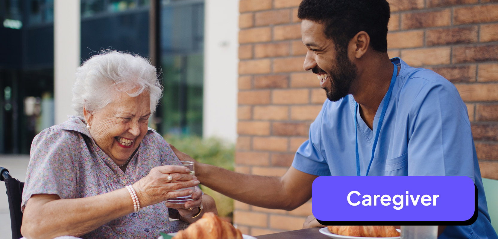 Male nurse sitting next to an elderly woman and acting as her caregiver