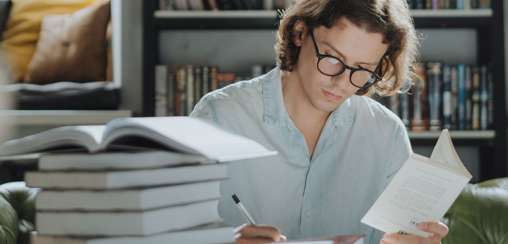 Proofreader sitting behind a large stack of books working on brushing up their knowledge for their side hustle