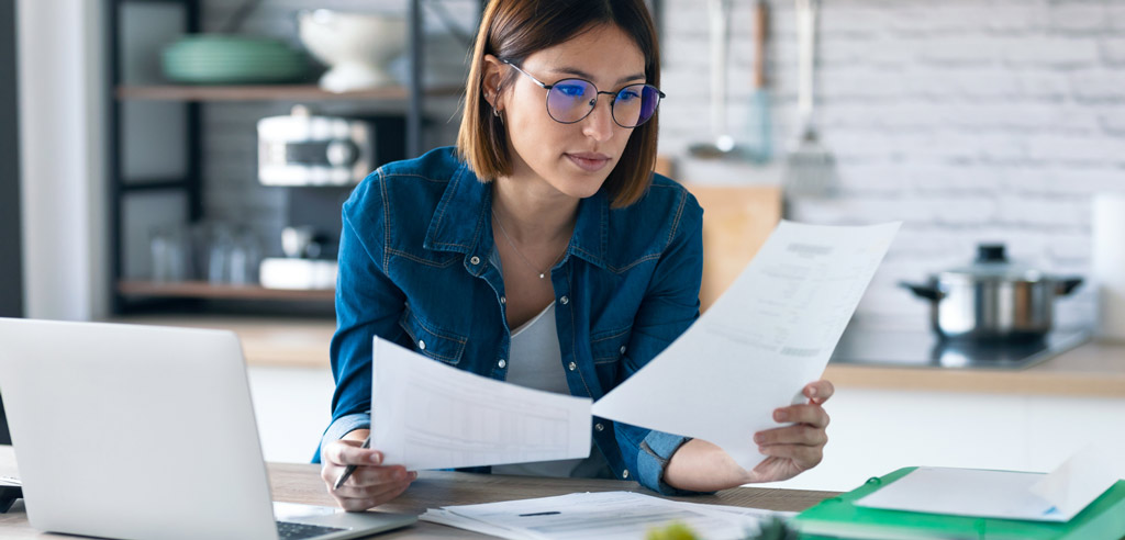 Freelance consultant examining several papers at her desk at home