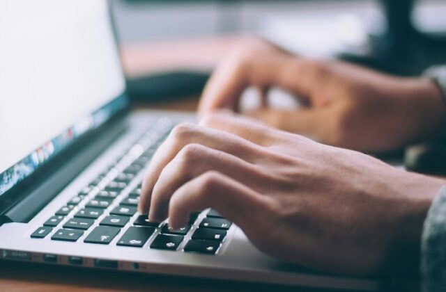 Close view of a job seeker working on their cover letter at their laptop.