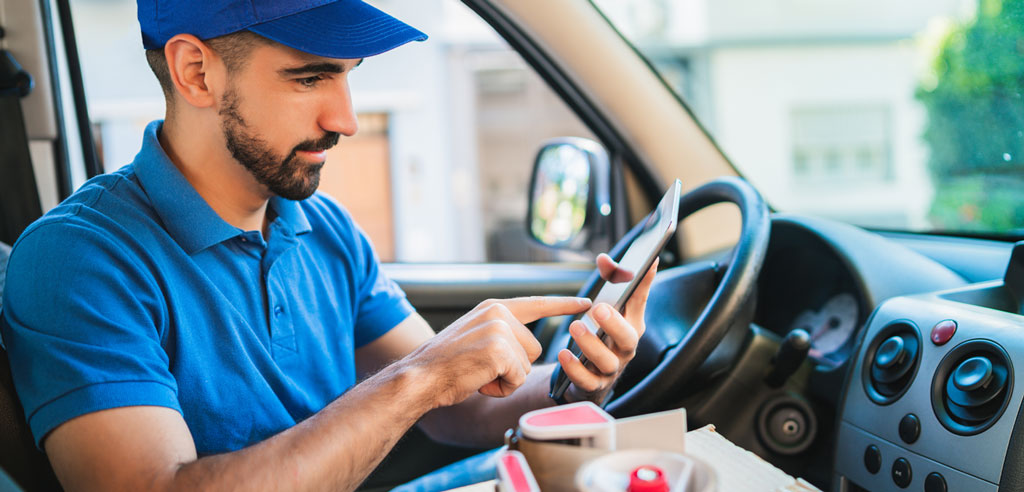 Part-time delivery driver entering an address into his phone