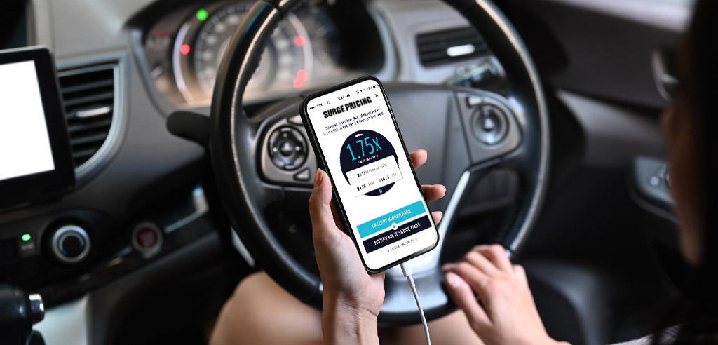 Rideshare driver sitting in her car, looking at her phone and considering surge pricing in the Uber app