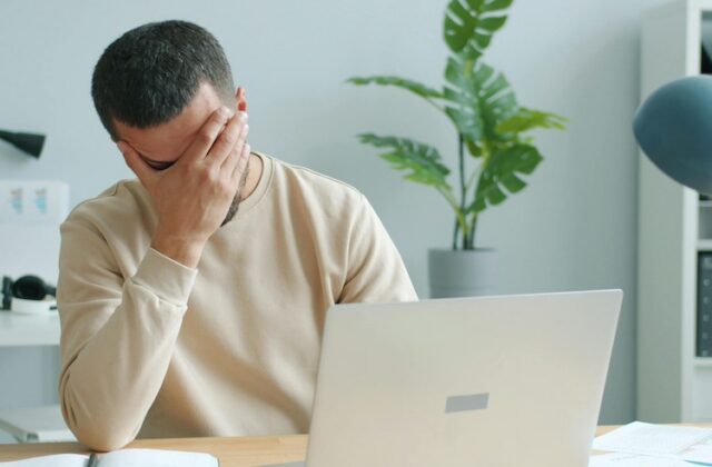 Frustrated job seeker looking for jobs on his laptop.