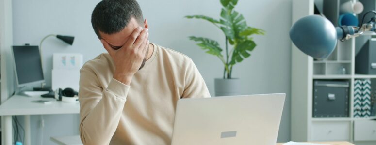 Frustrated job seeker looking for jobs on his laptop.
