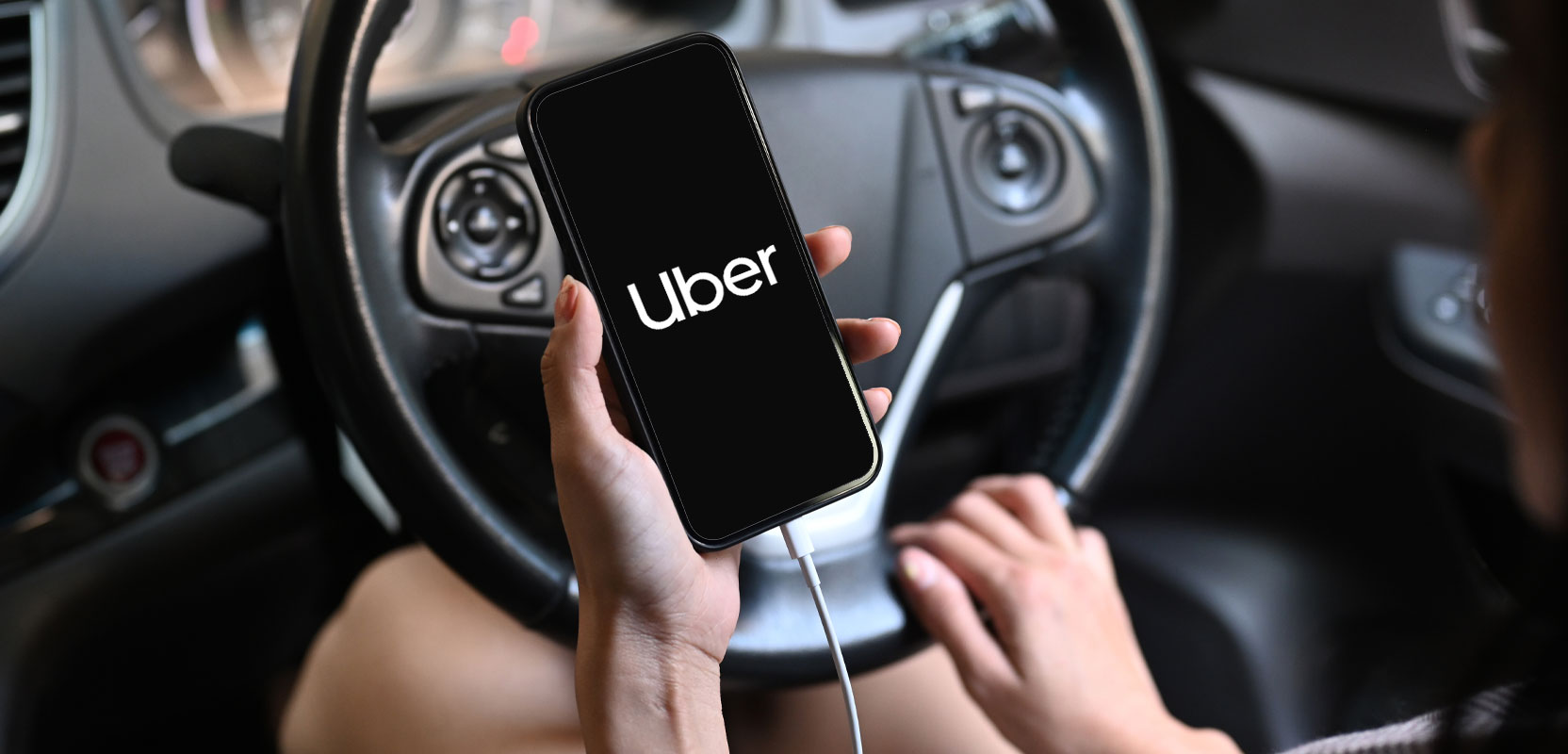 Uber driver charging their smartphone in their car while working their ridesharing side hustle