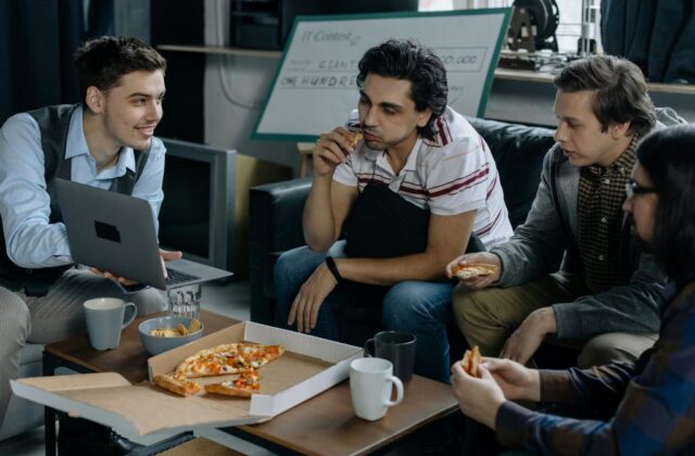 Employees sitting and eating pizza in their break room.