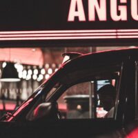 Favor driver waiting outside a restaurant for an order to be ready.